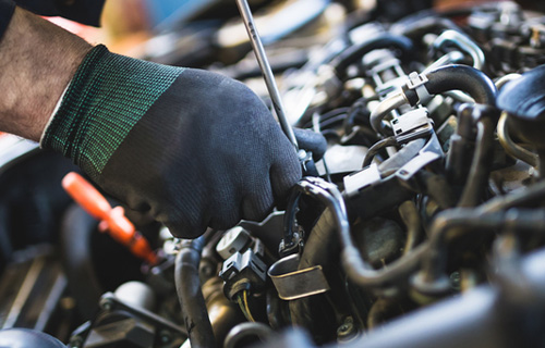 Mechanic's hand wearing a blue glove checking a car at a shop for auto repair in Safety Harbor