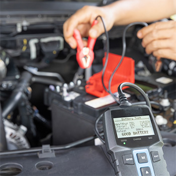 Mechanic's hand testing the voltage of a car battery