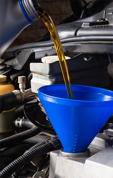 Oil poured into a blue car filter during oil change service.